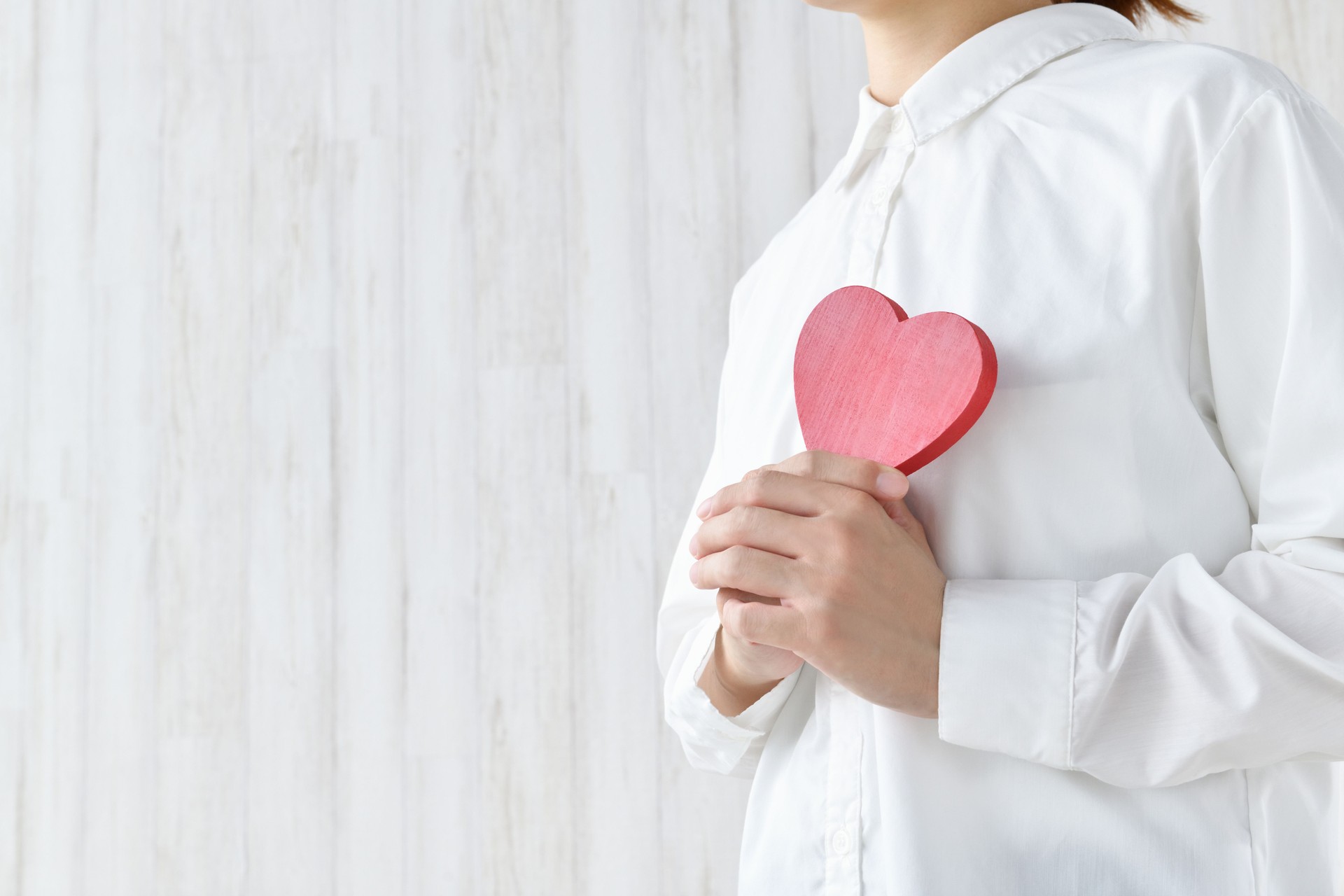Woman holding heart object on breast